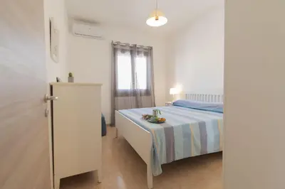 a white bedroom with a bed and a window at Appartamento La Loggetta a pochi metri dalla spiaggia di San Vito Lo Capo in San Vito lo Capo