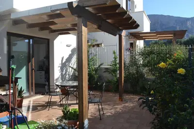 a patio with a table and chairs under a wooden pergola at Cale e Calle in Terrasini