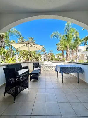 a patio with tables and chairs and an umbrella at casa NiKa a 150 mt dal mare in Isola delle Femmine