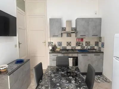 a kitchen with a table with chairs and a stove at Arco Apartment in Bagheria