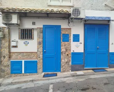 a building with blue doors on a street at Home sweet home in Santa Flavia