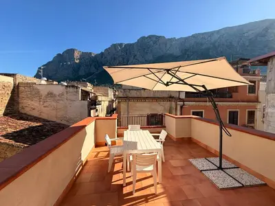 a patio with a table and an umbrella on a roof at Tampasiando Limoni in Cinisi