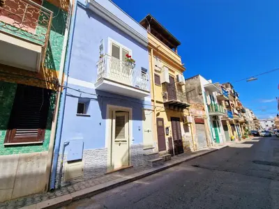 a street with a white building with a balcony at Casa Mo' in Isola delle Femmine