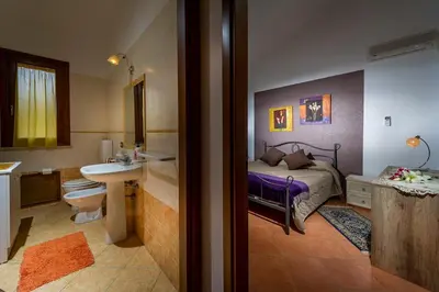 a bedroom with a bed and a bathroom with a sink at Villa del Carrubo in Castellammare del Golfo in Castellammare del Golfo