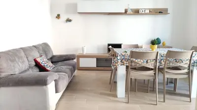 a living room with a couch and a table with chairs at Isola delle Femmine vacation home in Isola delle Femmine