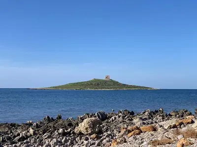 an island in the water with a lighthouse on it at Isola delle Femmine vacation home in Isola delle Femmine