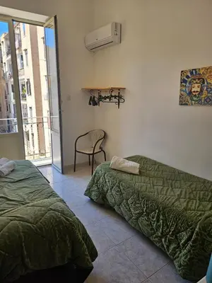 a bedroom with two beds and a chair and a window at Al Maqueda in Palermo