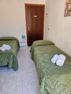 two beds in a room with green sheets at Al Maqueda in Palermo