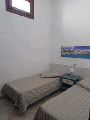 a room with two beds and a table and a window at il limone appartamenti 2 in San Vito lo Capo