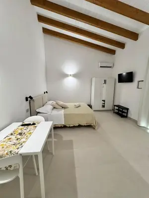 a white room with a bed and a table at Monolocale sotto la torre in San Vito lo Capo