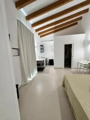 a bedroom with white walls and a wooden ceiling at Monolocale sotto la torre in San Vito lo Capo