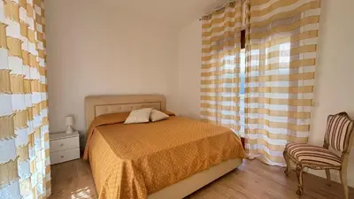 a bedroom with a bed and a chair and a window at Villa Emilia Mondello Appartamento Vita Alba con vista sul mare in Mondello