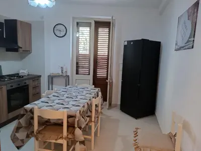a kitchen with a table with chairs and a black refrigerator at La casetta di Cecilia in Palermo