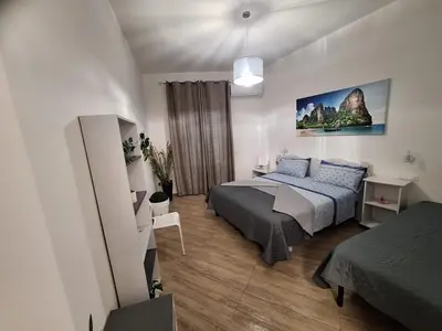 a bedroom with a bed and a desk and a bed and a room with at Normanni Deluxe Room Palermo in Palermo