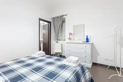 a white bedroom with a blue and white bed and a dresser at Casa Lulú in Palermo
