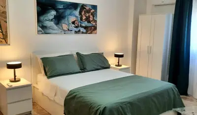 a bedroom with a bed with green sheets and a painting at Casa d'artista Max Serradifalco in Palermo