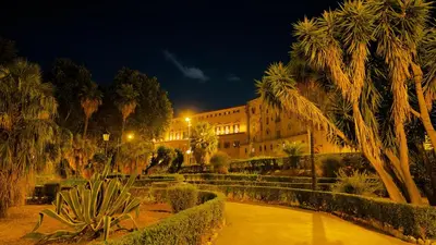 a building at night with palm trees and a pond at Pindemonte Pomelia in Palermo