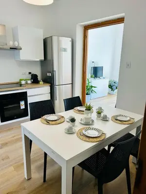a kitchen with a white table with chairs and a refrigerator at beach front bliss mondello in Palermo