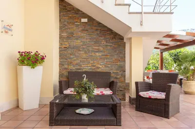 a patio with two wicker chairs and a table at Bed&Breakfast Acasamia in Castelluzzo