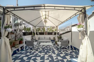 a patio with a white canopy and chairs and tables at Adenzia Suite in Palermo