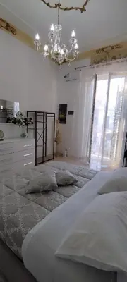 a large bed in a white room with a chandelier at Casa Vacanza Marion in Palermo
