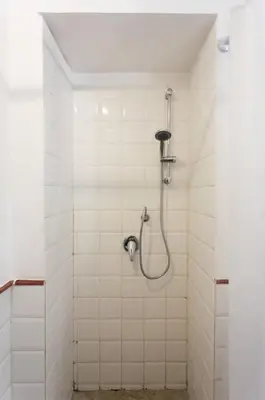 a shower in a white tiled bathroom with a hose at Dimora Alla Magione in Palermo