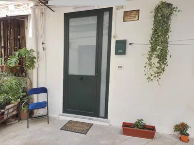 a green door on a white house with a blue chair at La casetta di John in Palermo