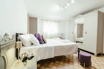 a white bedroom with a large bed with purple pillows at Nuccia's home vacanze in natura in Ficarazzi