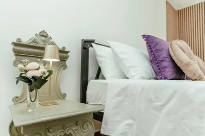 a bed with purple pillows and a table with a lamp at Nuccia's home vacanze in natura in Ficarazzi