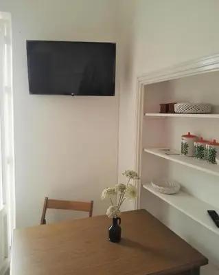 a room with a wooden table with a television on the wall at Villetta Casaurro in Bagheria
