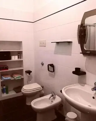 a white bathroom with a toilet and a sink at Villetta Casaurro in Bagheria
