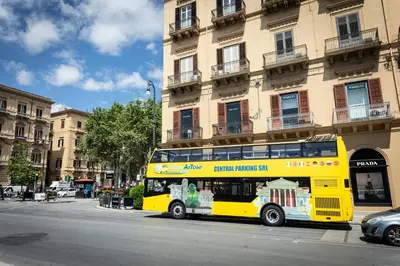 a yellow double decker bus parked in front of a building at Gravina 75 Rooms in Palermo