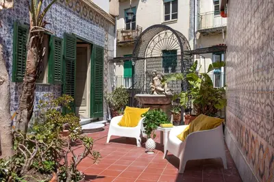 a patio with two white chairs and a fountain at iFlat Suite del Barone with Terrace in Palermo