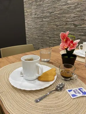 a cup of coffee on a plate on a table at Palermo Flowers Suites in Palermo