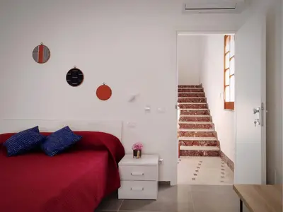 a bedroom with a red bed and a staircase at Cà Porto-Rooms with Balcony&Terrace in Santa Flavia