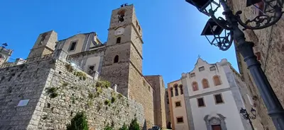 a building with a clock tower next to a wall at Casa del Vecchio Borgo in Caccamo
