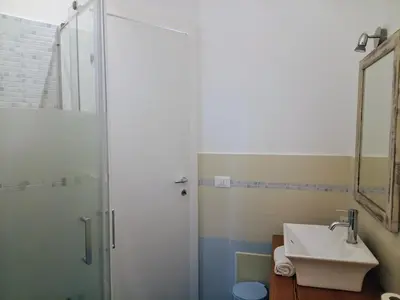 a bathroom with a sink and a shower with a mirror at Case Nereidi 3 in Porticello