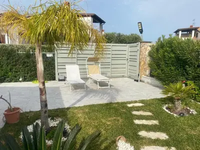 a patio with two chairs and a palm tree at Villetta SCHIRÒ - BAGNASCO in Campofelice di Roccella