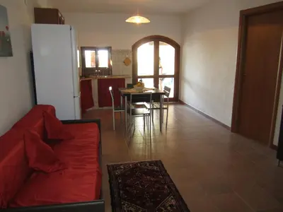 a living room with a red couch and a table at Casa Vacanze Daisy in Trappeto