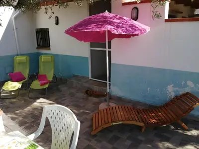 a purple umbrella and a bench and chairs at Casa Vacanze Daisy in Trappeto