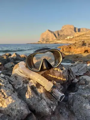 a pair of glasses sitting on some rocks near the water at Darling in Capaci
