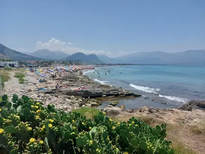 a beach with a crowd of people and the water at Darling in Capaci