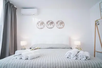 a white bedroom with a bed with towels on it at Encanto Apartment in Palermo