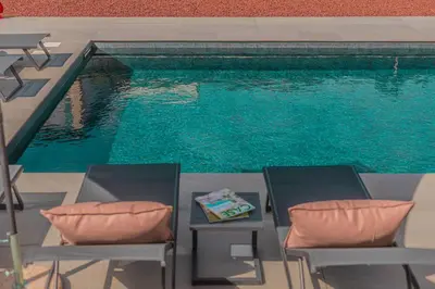 a pool with two chairs and a table next to a swimming pool at NAHIA Collection Villa in Campofelice di Roccella
