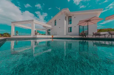 a villa with a swimming pool in front of a house at NAHIA Collection Villa in Campofelice di Roccella