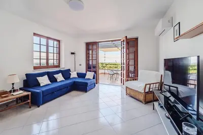 a living room with a blue couch and a tv at Pool & Panoramic Villa - 9 mins city center in Palermo