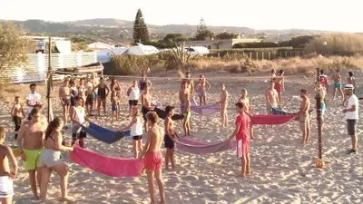 a group of people on a beach with chairs and umbrellas at Campeggio Praia Mare in Campofelice di Roccella