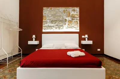 a bedroom with a red bed with two towels on it at IG Holiday in Cinisi