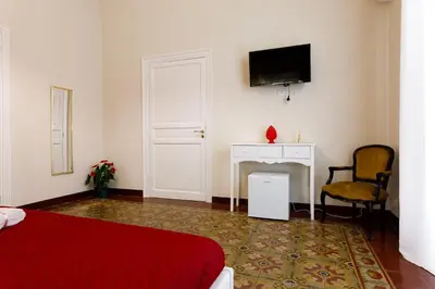 a bedroom with a bed and a desk and a tv at IG Holiday in Cinisi