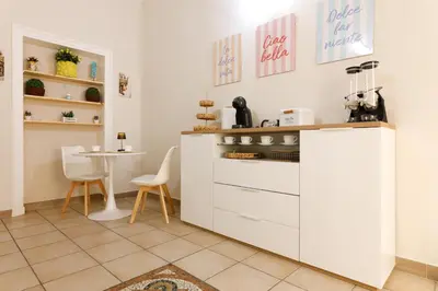 a kitchen with white cabinets and a table with chairs at IG Holiday in Cinisi